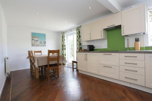 a kitchen with white cabinets and a dining room with a table at BOURNECOAST: Stones throw from the Quay - HB5666 in Bournemouth
