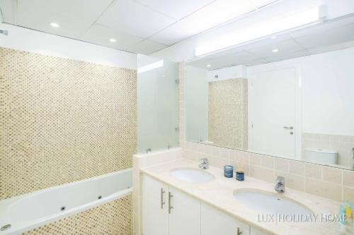 uma casa de banho com 2 lavatórios e um espelho grande em LUX The Meadows 5 Bed Villa em Dubai