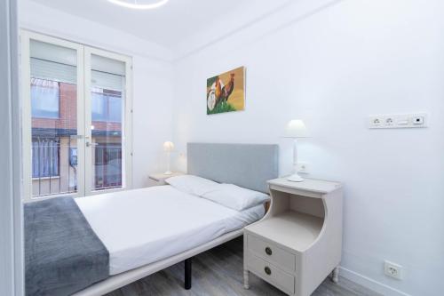 a white bedroom with a bed and a window at Piso reformado en el centro histórico PARKING GRATIS Check-in 24 h in Zaragoza