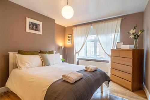ein Schlafzimmer mit einem Bett mit einer Kommode und einem Fenster in der Unterkunft Location! 2 bed/2bath - Pro Host in London