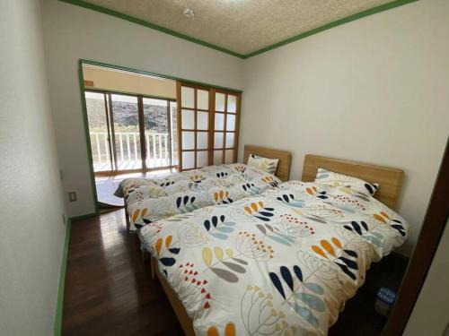 1 dormitorio con 2 camas y ventana grande en 森の中のぽつんとワンワン別荘, en Nikko