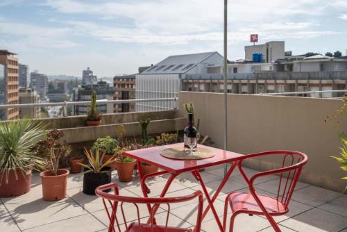 a red table and chairs on a balcony with plants at Modern Luminous Rooftop Apartment in Porto