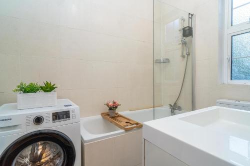 a bathroom with a washing machine and a bath tub at Location! 2 bed/2bath - Pro Host in London
