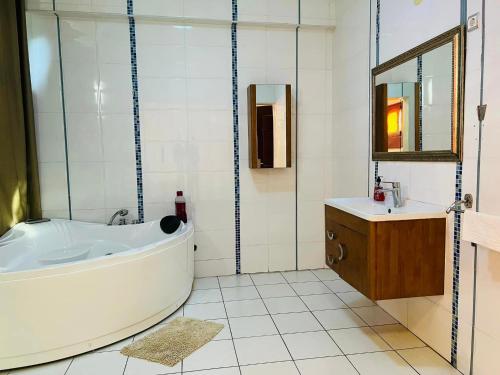 a bathroom with a tub and a sink and a mirror at TRMOTEL in Matola
