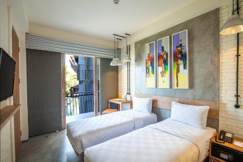 two beds sitting in a room with a window at FRii Bali Echo Beach in Canggu