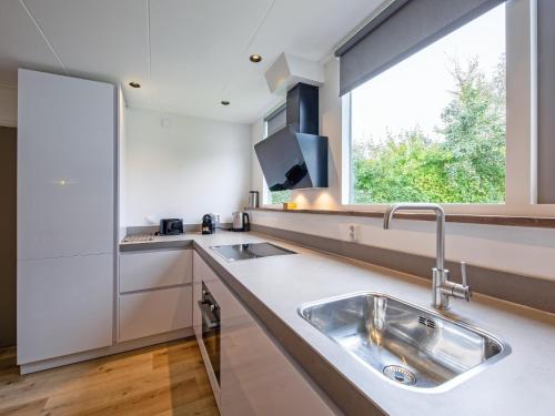 a kitchen with a sink and a large window at Cozy holiday home with hot tub on Texel in Den Burg