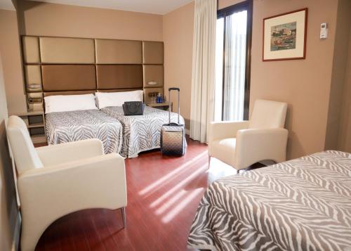 Habitación de hotel con 2 camas y 2 sillas en Hotel Benetusser, en Benetúser