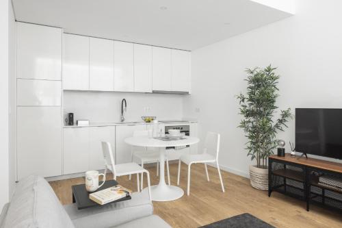 a white kitchen with a white table and chairs at Aveiro Urban Twins in Aveiro