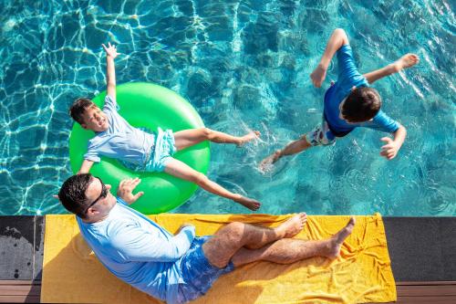 a group of people jumping in a swimming pool at Centara Mirage Beach Resort Dubai in Dubai
