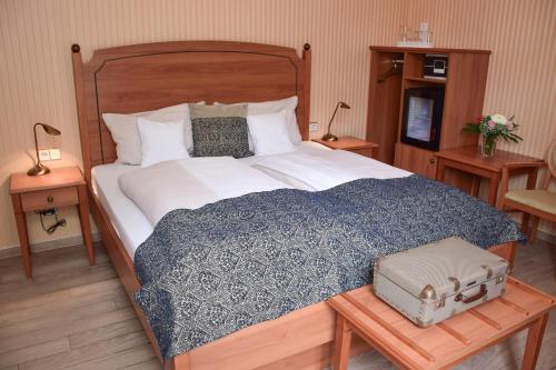 a bed with a blue and white blanket and a suitcase at Hotel Barbara in Freiburg im Breisgau