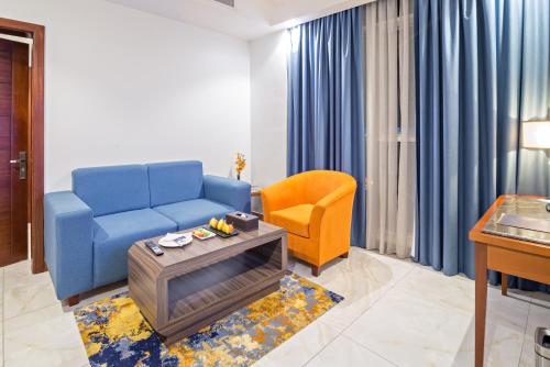 a living room with a blue couch and a chair at Jiwar Almasi Hotel in Jeddah