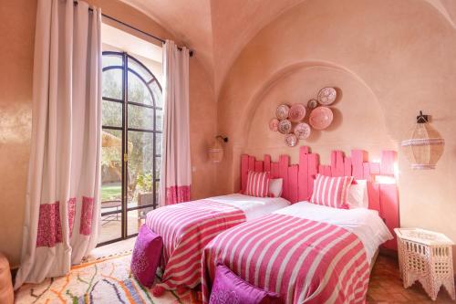 two beds in a room with a window at Villa Serena Marrakech - Maison d'hôtes in Marrakech