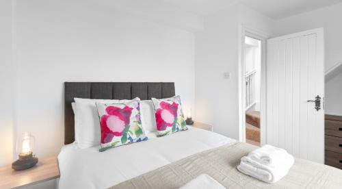 a white bedroom with a bed with pink flowers on it at Well Coach House by Cliftonvalley Apartments in Bristol