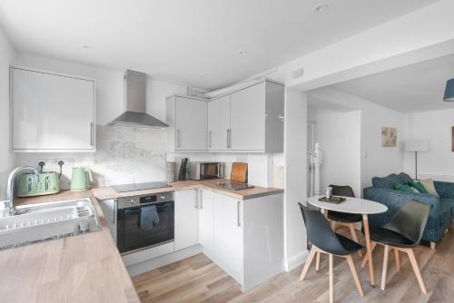 a kitchen with white cabinets and a table and chairs at Well Coach House by Cliftonvalley Apartments in Bristol