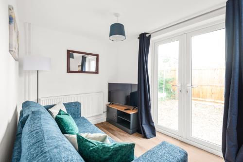 a living room with a blue couch and a sliding glass door at Well Coach House by Cliftonvalley Apartments in Bristol