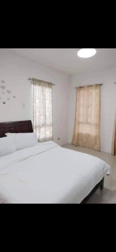 a bedroom with a large white bed and two windows at Vacation home in Lancaster new city Cavite Philippines in General Trias