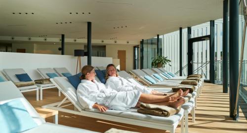 two women sitting on lounge chairs in a room at Hotel Stoiser in Loipersdorf bei Fürstenfeld