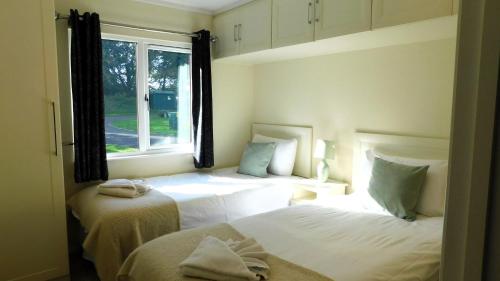 1 dormitorio con 2 camas y ventana en The Lodge, Alder Country Park, en North Walsham