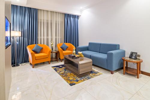 a living room with a blue couch and two orange chairs at Jiwar Almasi Hotel in Jeddah