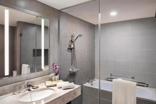 a bathroom with a sink and a tub and a mirror at Hilton Garden Inn Puchong in Puchong