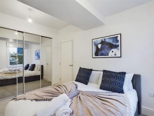 1 dormitorio con 1 cama blanca grande con almohadas azules en The Grove King bed Wi-Fi EV Charger en Cheltenham