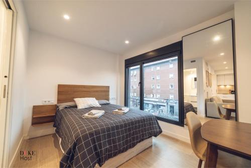 a bedroom with a bed and a table and a window at CASTILLA LUXURY A Apartments in Madrid