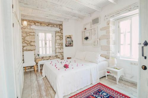 a white bedroom with a white bed with flowers on it at YUKARI SOKAK VİP BUTİK OTEL in Alacati