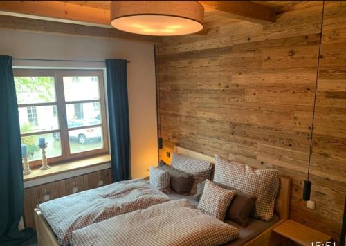 1 dormitorio con pared de madera y cama con almohadas en Moarhof Ferienwohnung1 en Dietramszell