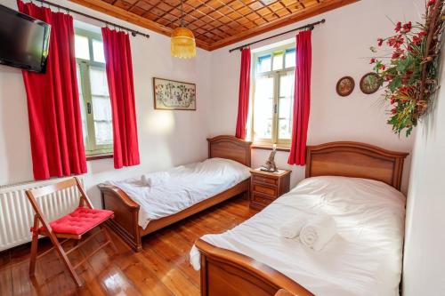 two beds in a room with red curtains at Timfea Chalet in Tsepelovo