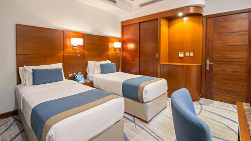 a hotel room with two beds and a chair at Jiwar Almasi Hotel in Jeddah