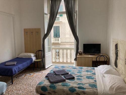 a bedroom with two beds and a window with a television at Guest House Roma in Genoa