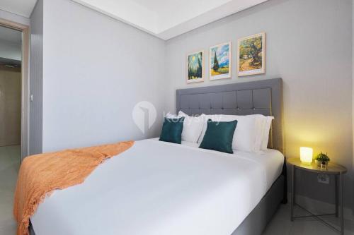 una camera da letto con un grande letto bianco con cuscini verdi di Sonrisa by Kozystay - Studio - Ocean View - PIK a Giacarta