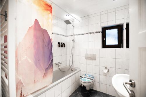 a bathroom with a tub and a toilet and a sink at Alpina Haus in Oberammergau