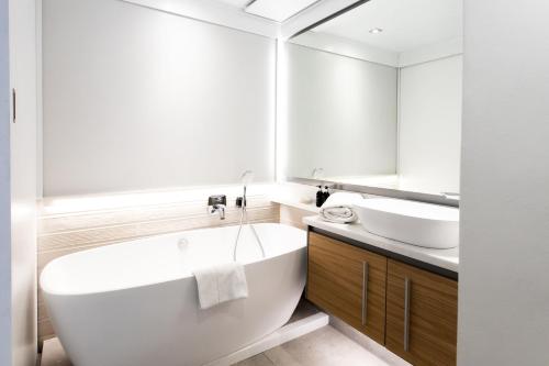 La salle de bains est pourvue d'une grande baignoire blanche et d'un lavabo. dans l'établissement Bayview 104, à Hermanus
