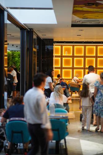 a group of people sitting at tables in a restaurant at Royal G Max in Golem