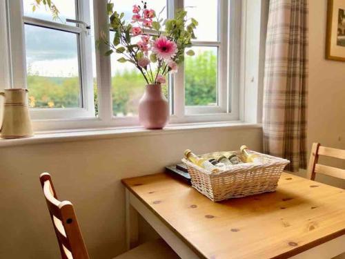 a table with a basket of flowers in a window at Scenic Couples Getaway in the Brecon Beacons in Crickhowell