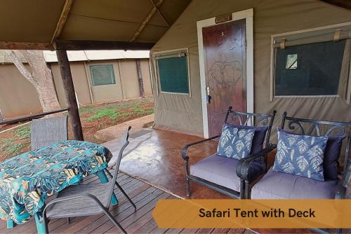 a porch with two chairs and a table and a door at Crocodile Bridge Safari Lodge in Komatipoort