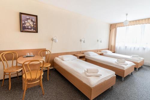 a room with three beds and a table and chairs at Hotel Alf in Kraków
