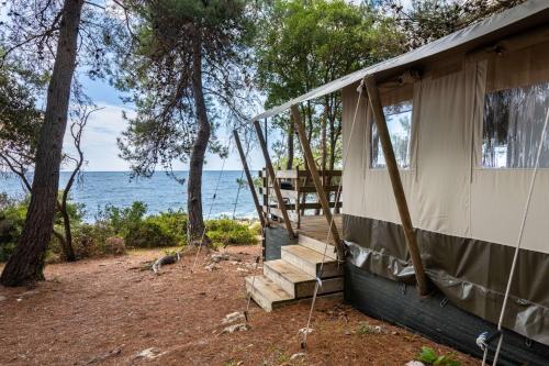een huis met een veranda en een schommel bij Easyatent FKK Safari tent Koversada Naturist - clothes free in Vrsar