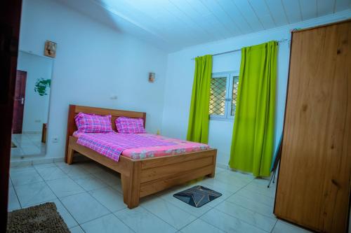 a bedroom with a bed and green curtains at Appartement Meublé Bonamoussadi Douala in Deido