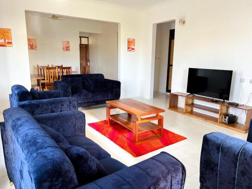a living room with blue couches and a coffee table at Kijiji Villas Nungwi in Banda Kuu