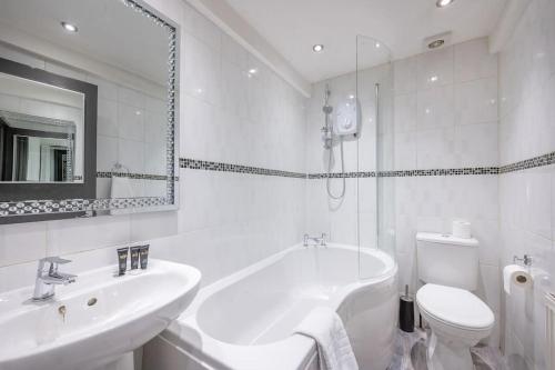 uma casa de banho branca com uma banheira, um lavatório e um WC. em *F4GH for your most relaxed & Cosy stay + Free Parking + Free Fast WiFi * em Bramley