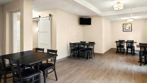 a room with tables and chairs and a television at Magnuson Hotel Detroit Airport in Romulus