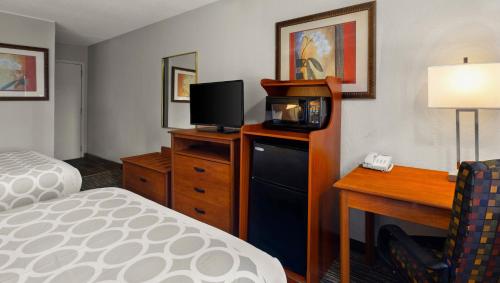 a hotel room with a bed and a desk with a microwave at Magnuson Hotel Detroit Airport in Romulus