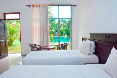 two beds in a hotel room with a view of a pool at Siyanco Holiday Resort in Polonnaruwa