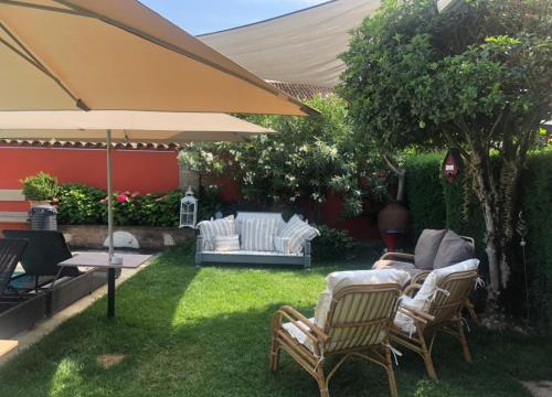 un patio trasero con 2 sillas y una sombrilla en B&B Villa la Canonica a Padernello, 
