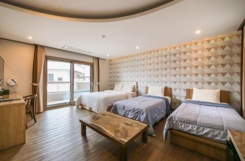 Habitación de hotel con 2 camas y mesa en Rex Hotel, en Seogwipo