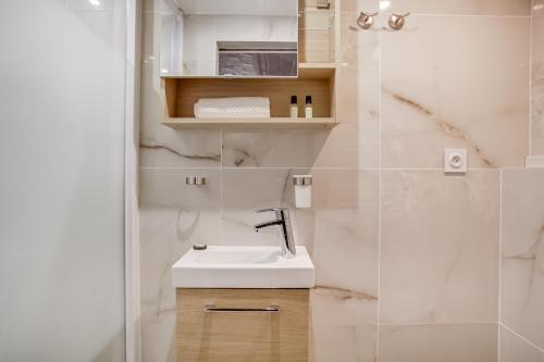 une salle de bain blanche avec un lavabo et une douche dans l'établissement Tiny Duplex with Sauna in the 11, à Paris
