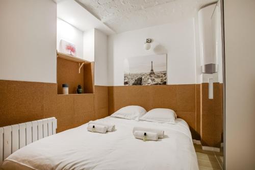 une chambre avec un grand lit blanc avec des serviettes dessus dans l'établissement Tiny Duplex with Sauna in the 11, à Paris