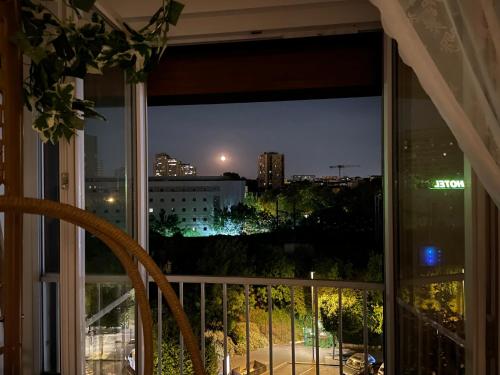 una ventana con vistas a la ciudad por la noche en Rose Blossom apartment in Paris en Vanves